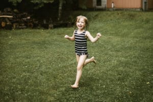 A young girl running around the backyard after a warm family sauna