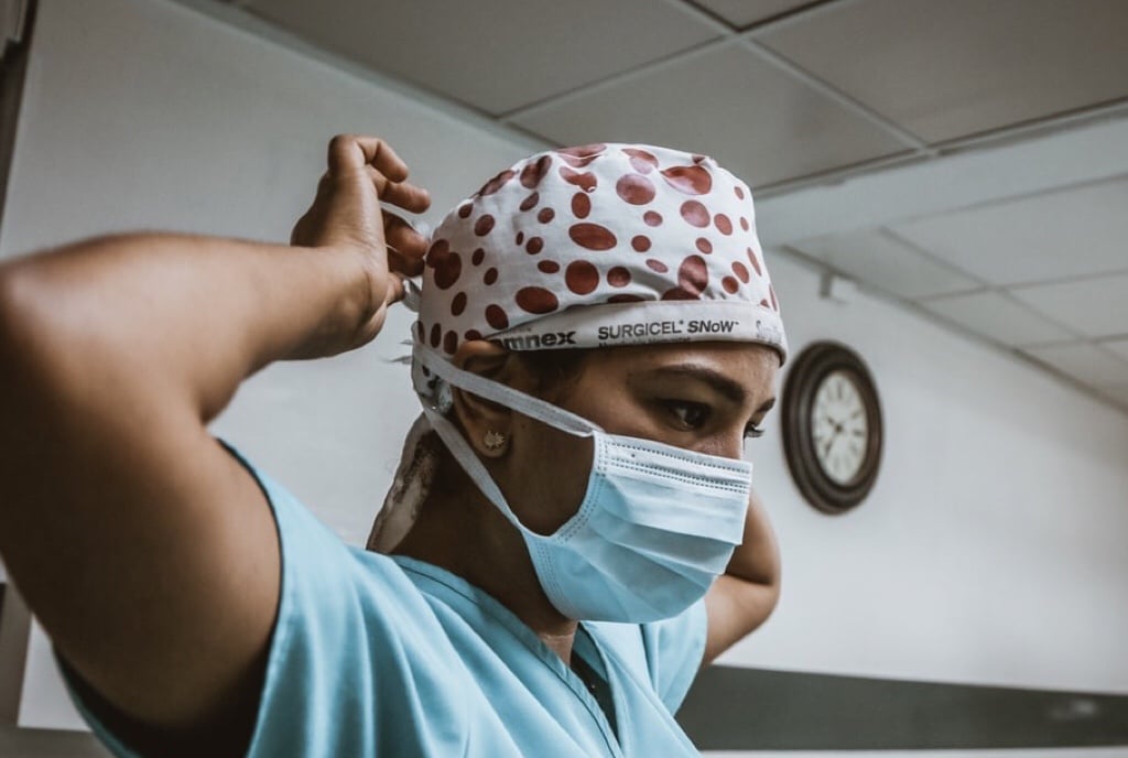A female healthcare worker adjusting her surgical mask